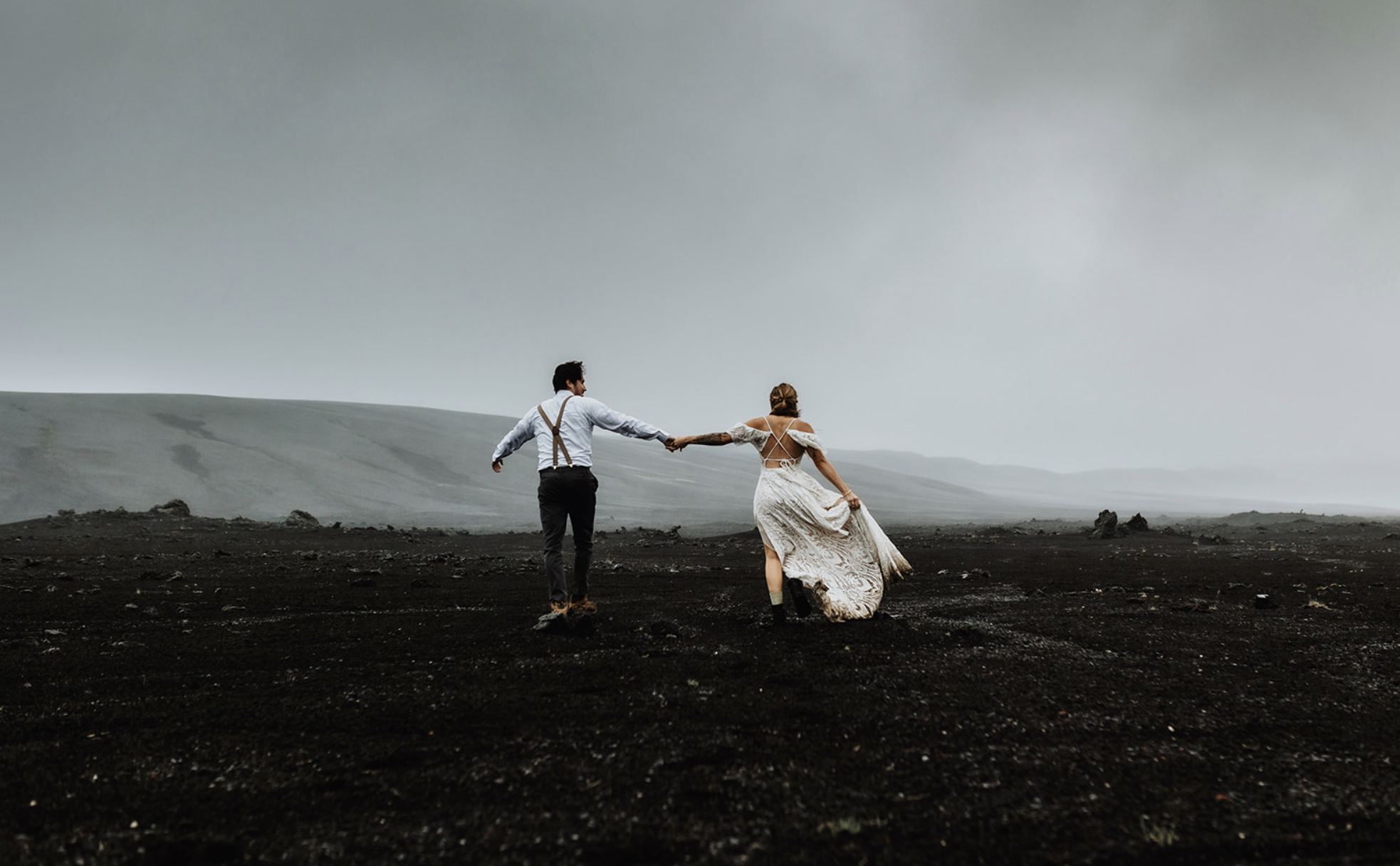 Married couple is walking in the dramatic landscape of the Icelandic Highlands on their wedding day