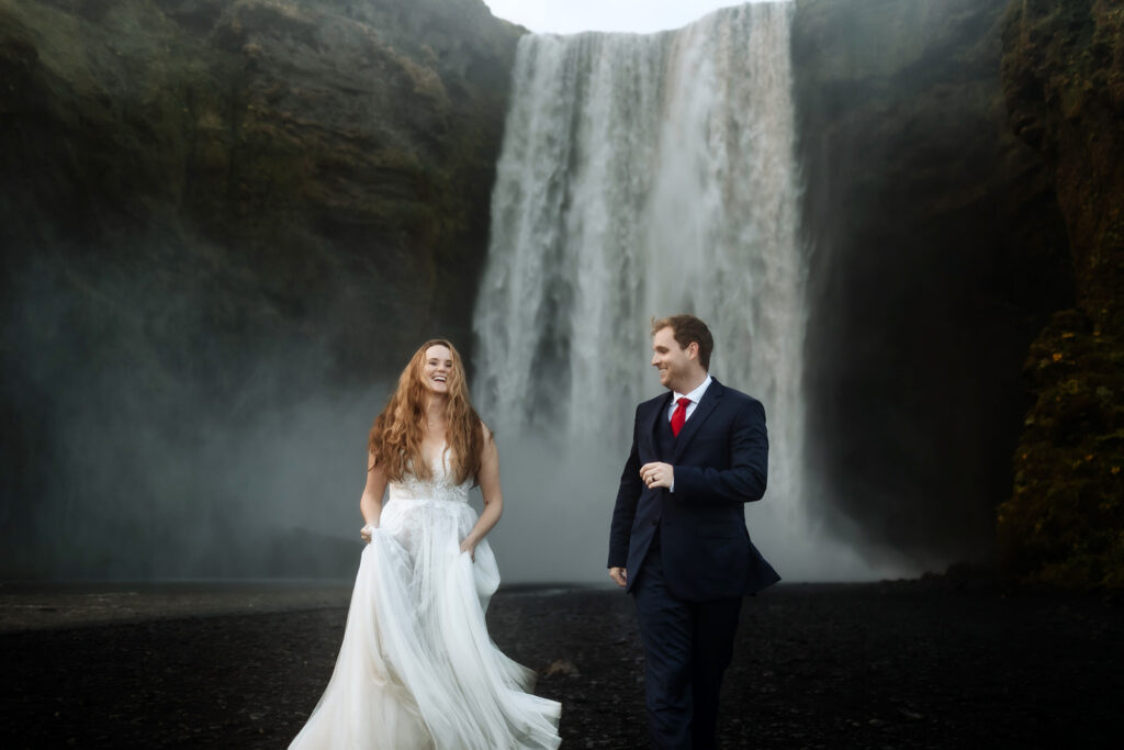 Kimberly and Blake in their wedding clothes in the mist of Skógafoss