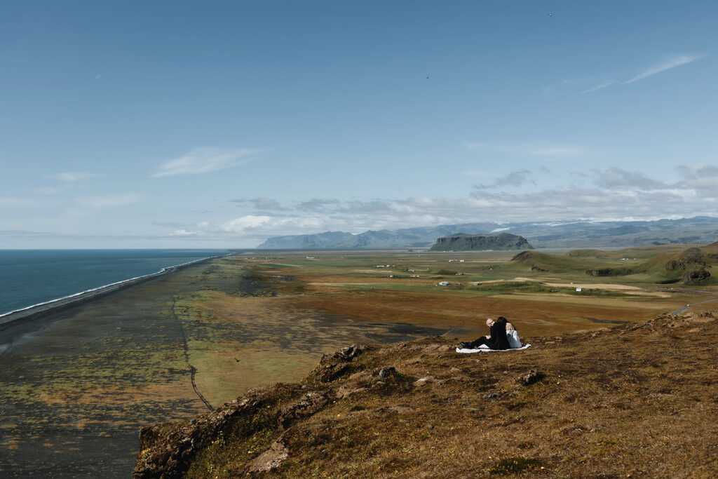 Young couple Jade and Bradley are writing their vows at Dyrholaey Iceland on a sunny day