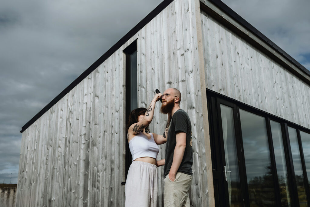 young couple Jade and Bradley are getting ready for their elopement. Jade is shaving Bradley in front of their cabin