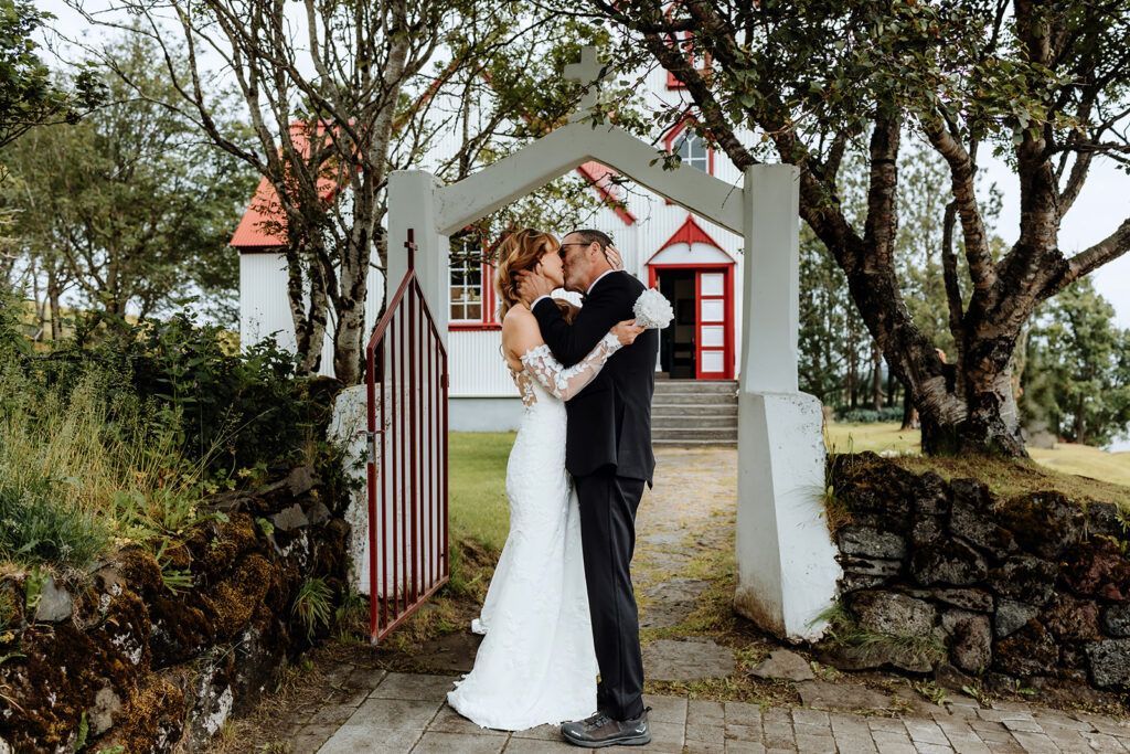 Tracie and Jay kissing in front of Breiðabólstaðarkirkja church