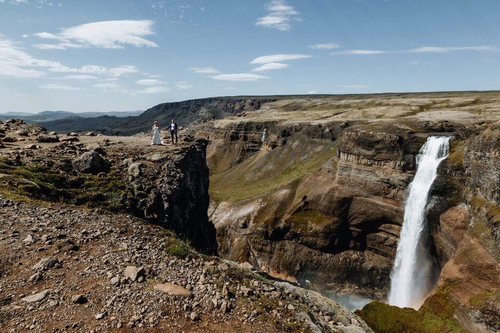 Tracie and Jay at the edge of the canyon above Háifoss waterfall on a sunny day