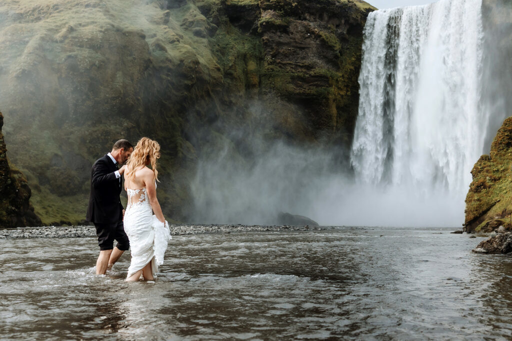 Tracie and Jay barefoot in the flooded glacier water in front of Skógafoss